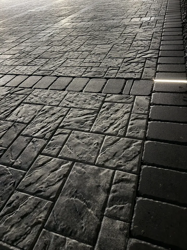 Detail of slate-textured charcoal pavers set tight against a straight border course, joints filled and flush
