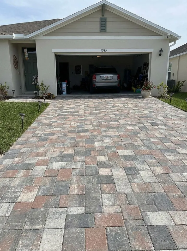 Random-ashlar driveway in gray, tan and terracotta pavers leading to a two-car garage