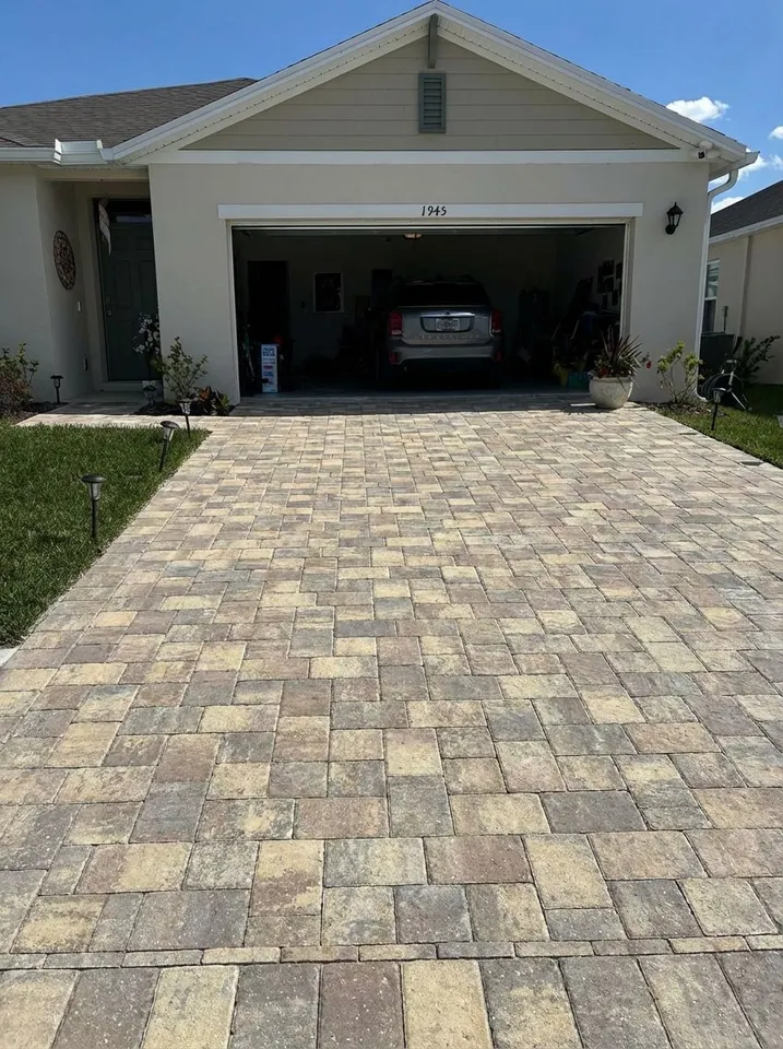 Tan and gray paver driveway laid in a random pattern, edged by lawn and low solar path lights